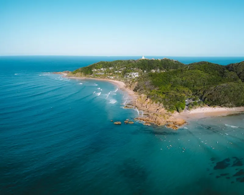 Cape Byron headland from the air, with the lighthouse on top and clear turquoise water below