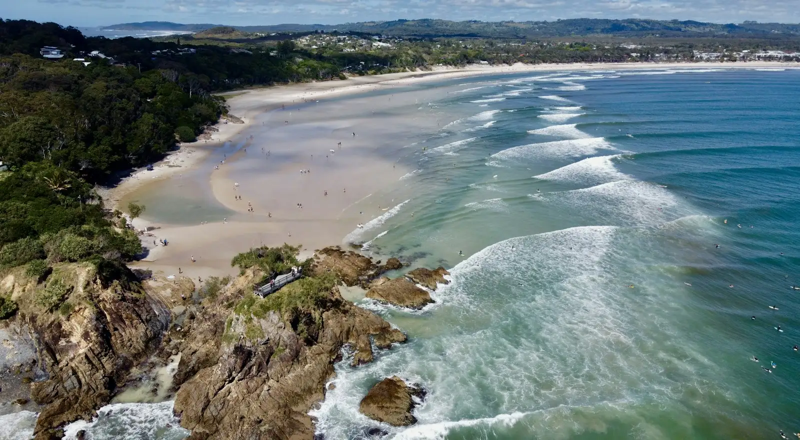 Aerial view of The Pass and the long curve of beach towards Byron Bay, with waves rolling in